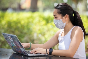 UF student sitting looking at her computer wearing a mask.