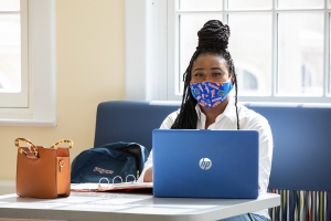 UF student on her computer wearing a mask.