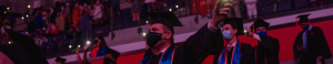 A student with a mask hold a phone while in commencement ceremony.